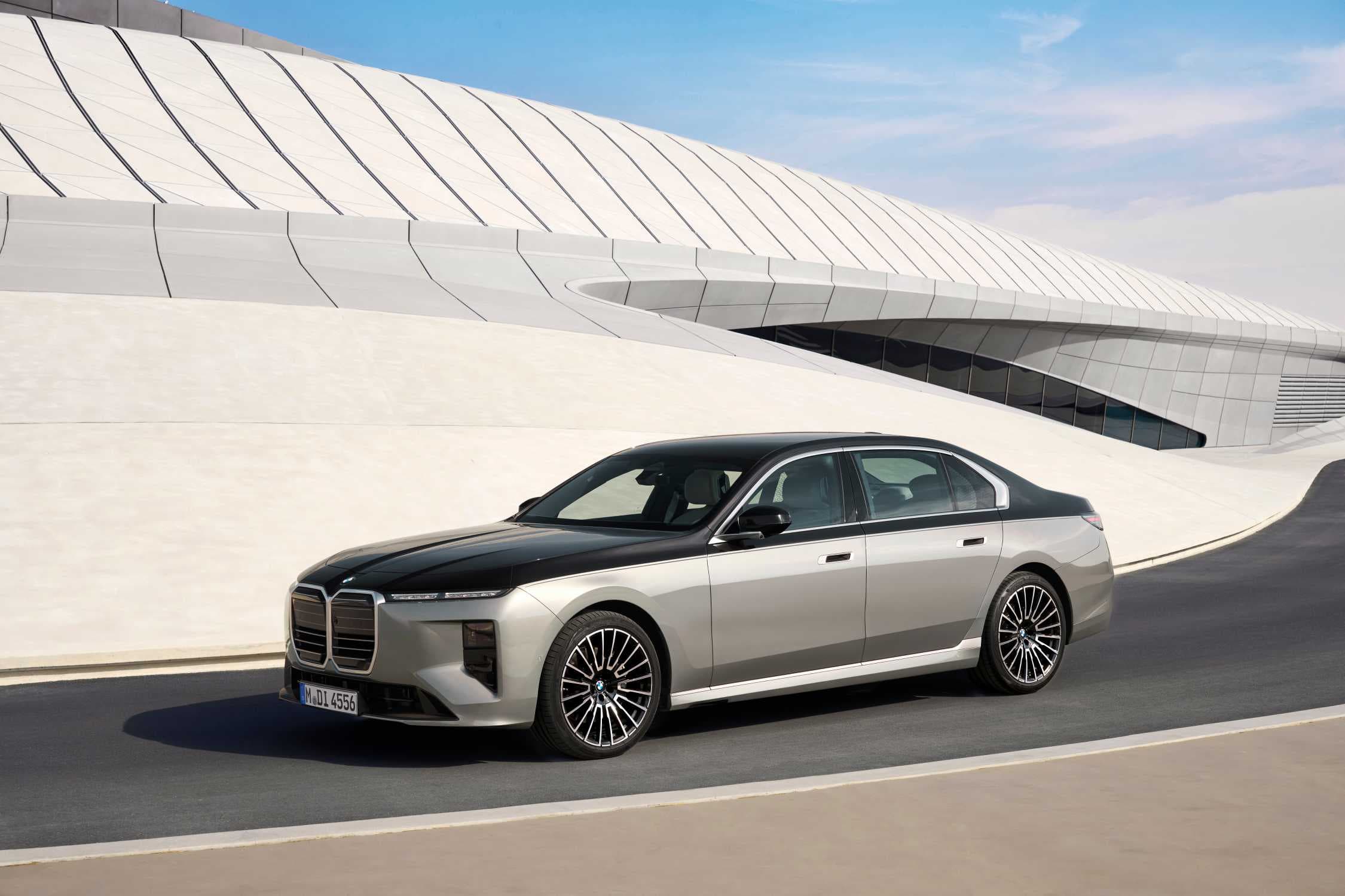 부분변경된 BMW 740 xDrive 세단, 위는 검정·아래는 은색인 투톤 도장으로 곡선 건물 앞 도로를 달리는 측면 모습