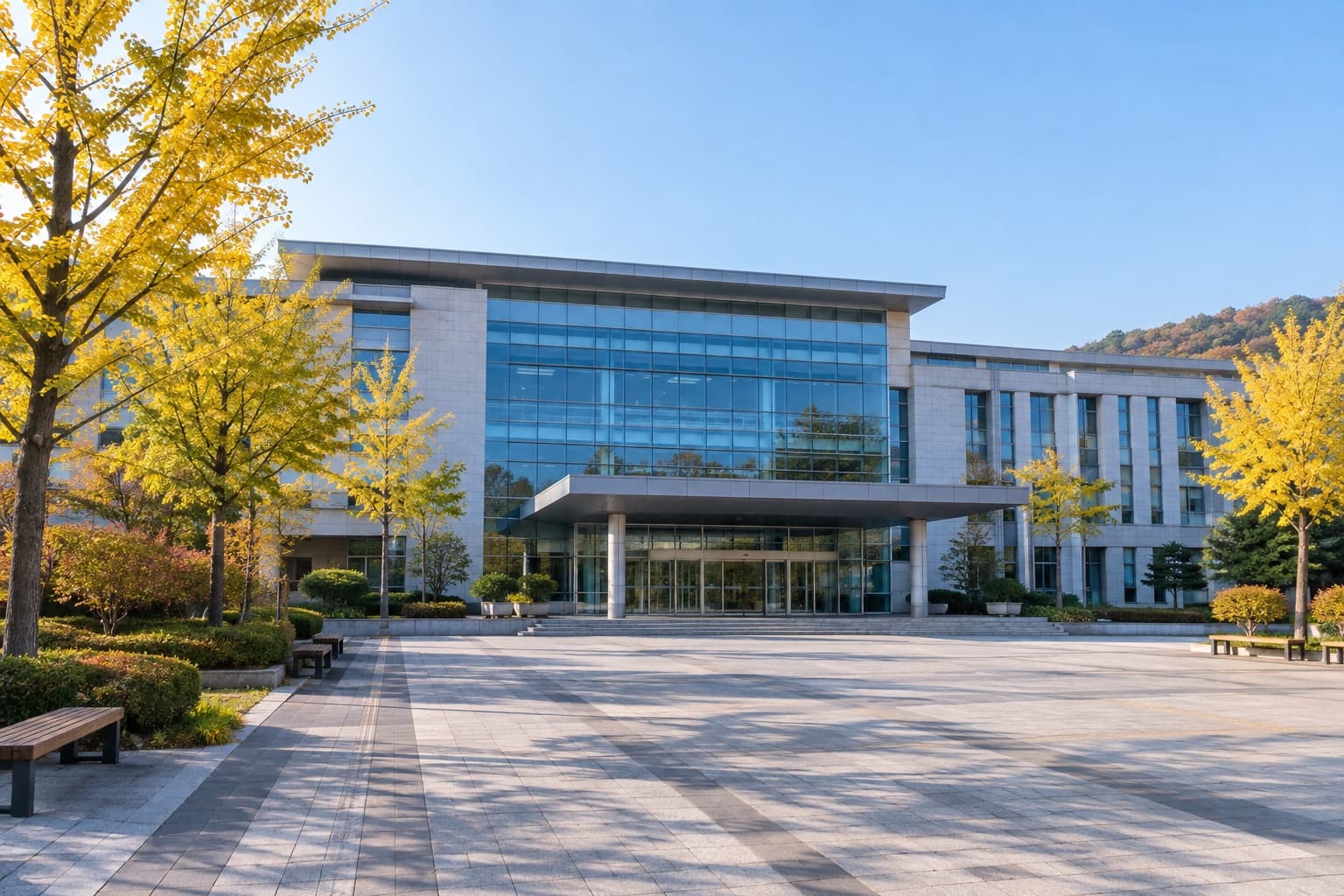 맑은 가을 아침, 은행나무가 물든 빈 광장 너머의 유리 외벽 청사 건물 (AI 생성 이미지)