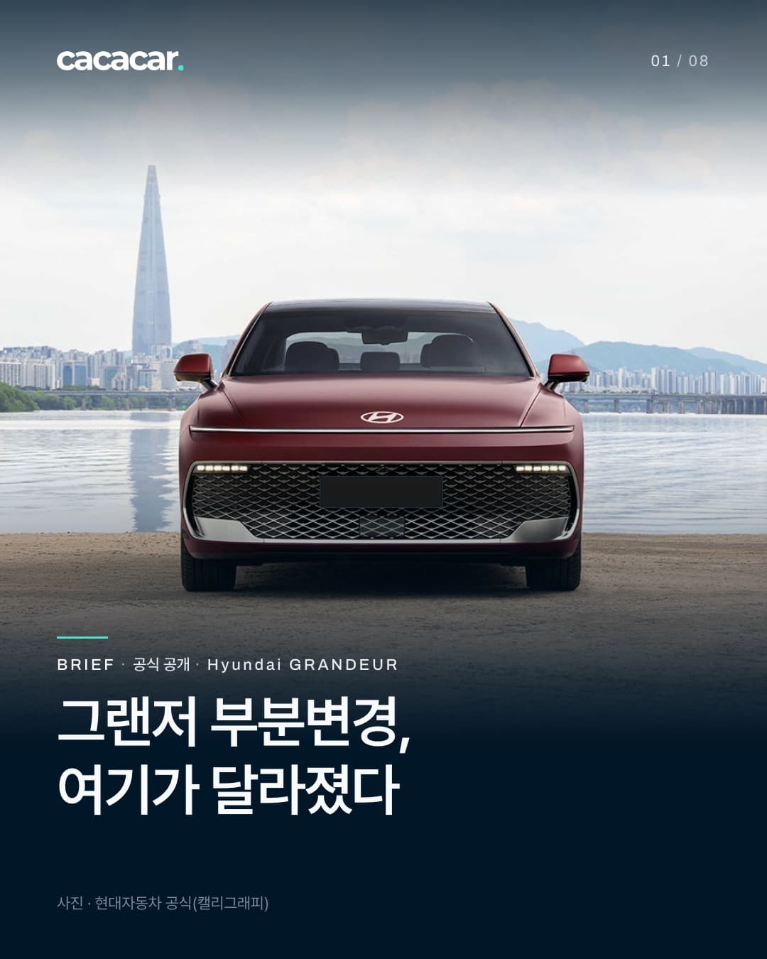 표지. 한강 모래사장과 강 건너 도심 스카이라인을 배경으로 정면에서 본 더 뉴 그랜저. 앞머리를 가로로 잇는 얇은 램프 줄이 켜져 있고 번호판은 단색으로 가렸으며, 제목은 '그랜저 부분변경, 여기가 달라졌다'.
