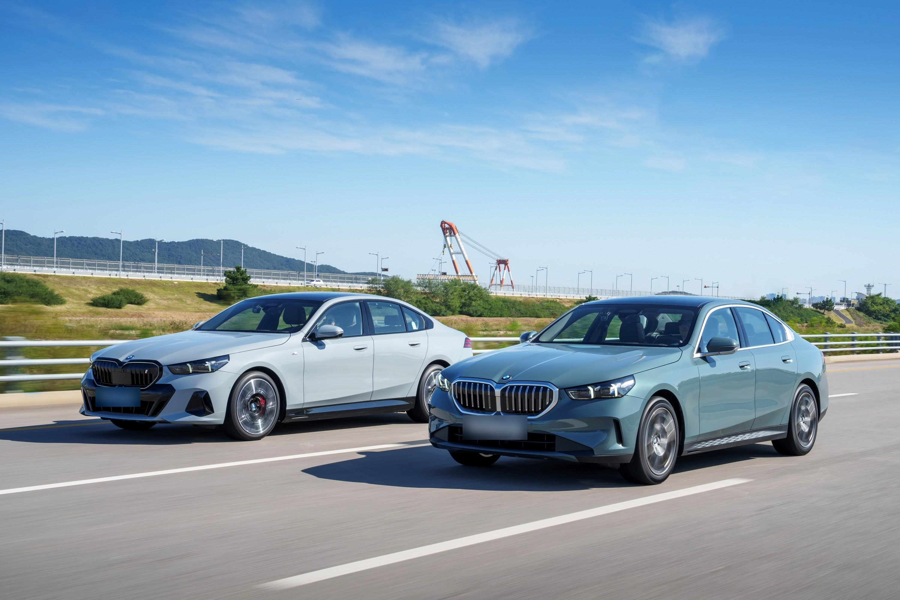 고속도로를 달리는 BMW 5시리즈 두 대, 앞쪽 청록색 520i와 뒤쪽 회색 세단 (번호판 가림)