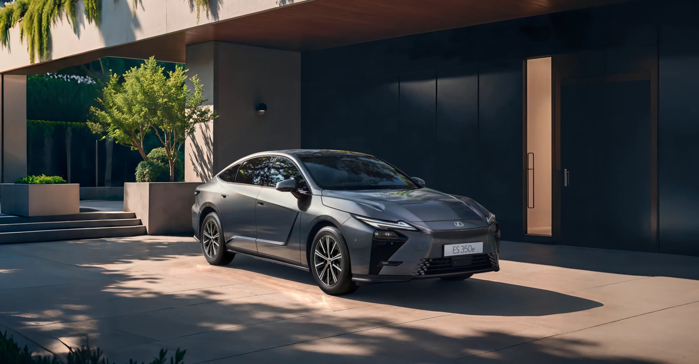 현대적인 건물 앞에 선 회색 렉서스 All-New ES 350e 전면. 가늘게 뻗은 주간주행등과 구멍이 적은 매끈한 앞범퍼가 보이는 렉서스코리아 공식 이미지